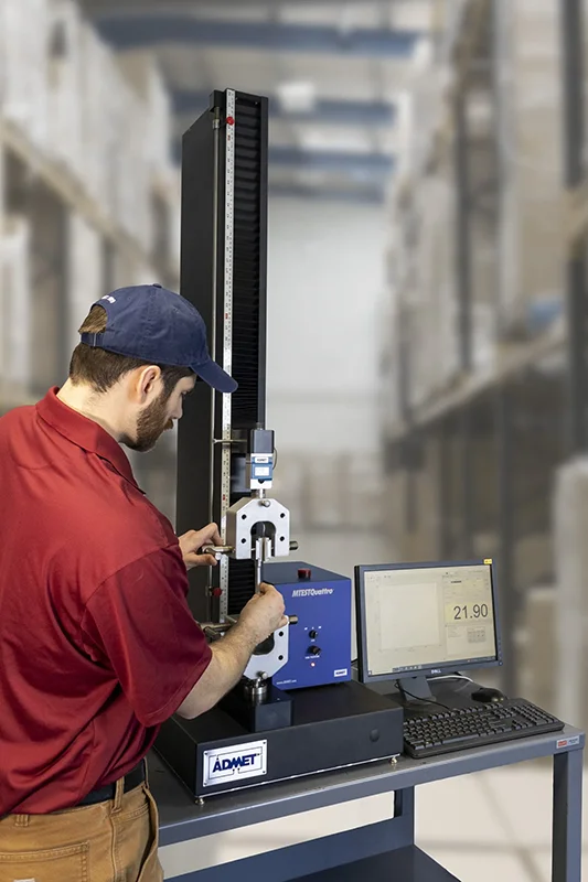 Operator setting up a tensile test on a universal testing machine