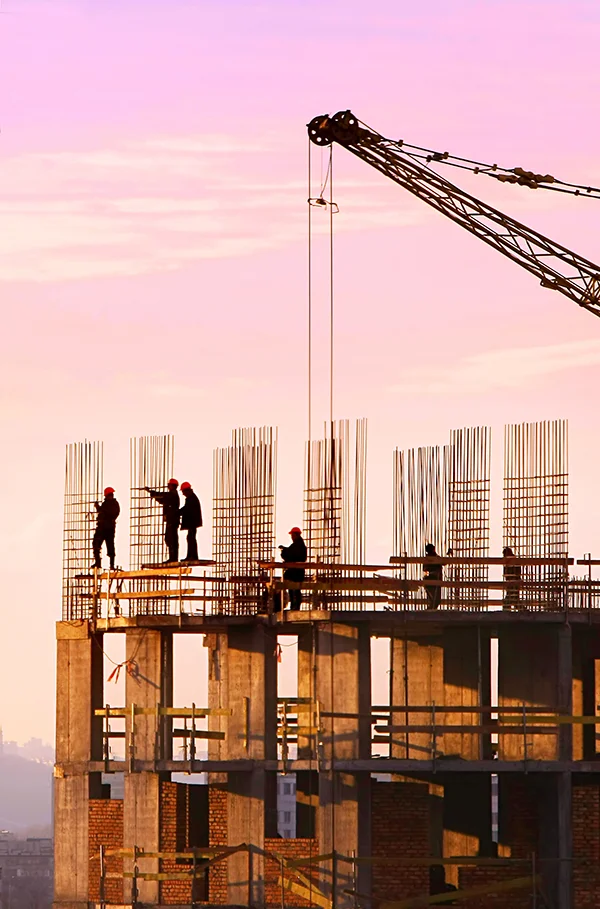 Construction workers on a building site at sunset.